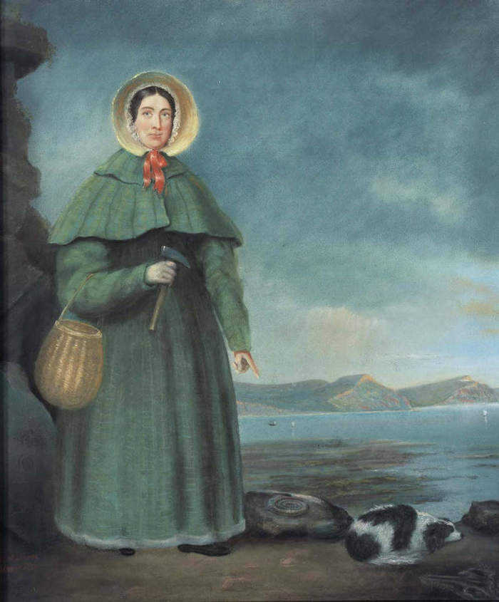 This portrait shows Mary Anning decked out in middle class Georgian clothing of the time.  This would have been the most formal outdoor wear Mary had.  According to Eleanor Emma Warings writings, Mary would have been more plainly dressed while fossil collecting.  The Golden Cap outcrop is behind her in the distance.  It also shows Mary Anning's dog named Tray.    Unfortunately, the fluffy fossil hunting companion was killed in an 1833 cliff fall that almost killed Mary Anning. (Public Domain))